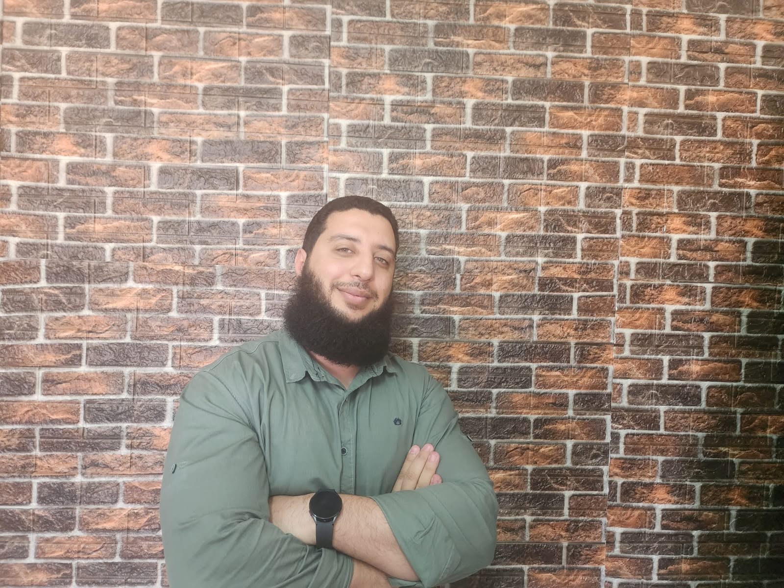 Mohammed Elmahdy standing with arms crossed in front of a brick wall